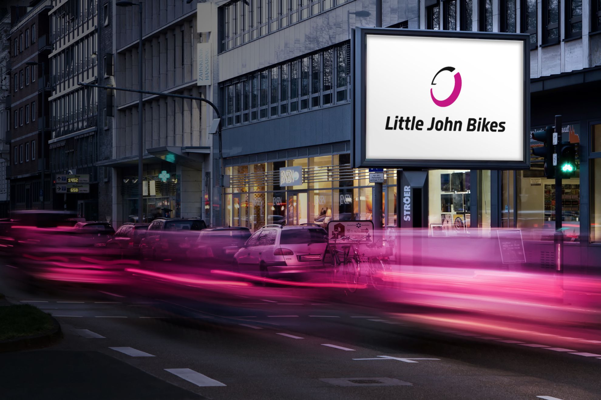 Werbeplakat zeigt das Logo von Little John Bikes in Großstadt, dynamische Schrift, im Vordergrund verwischte Lichter von Autos