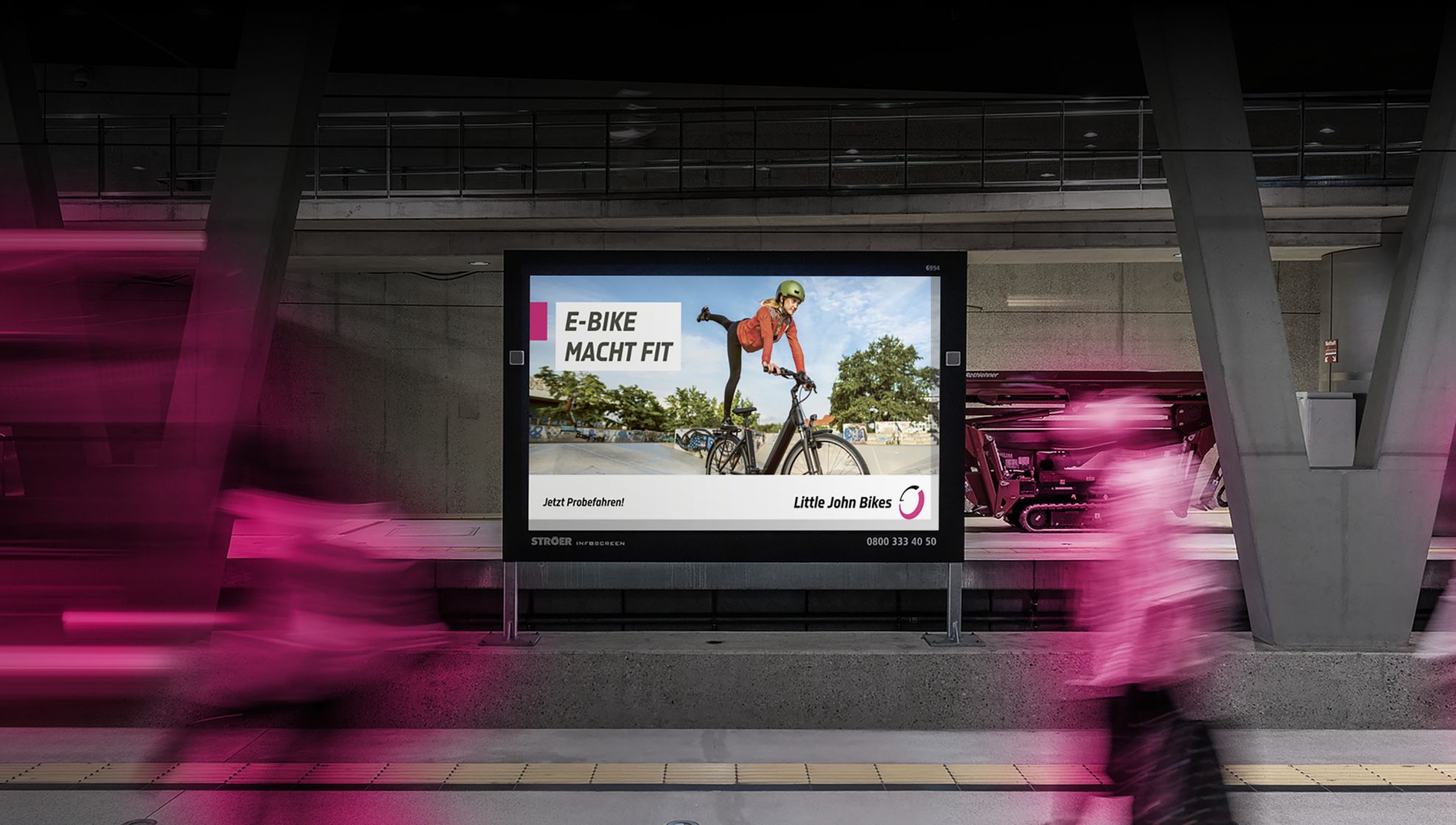 Werbeplakat von Little John Bikes in Großstadt an einem Bahnhof, dynamische Schrift, im Vordergrund verwischte Lichter von einem abfahrenden Zug