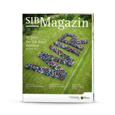 Titelmotiv des Jubiläumsmagazins zum 20 jährigen Jubiläum des SIB. Auf dem Titel sind die Mitarbeiter des SIB aus der Vogelperspektive zu sehen. Diese stehen auf einer Wiese und bilden das Wort "WIR".
